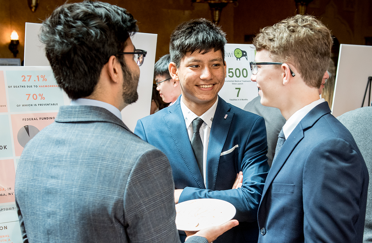 Three male students during a project presentation in business attire.