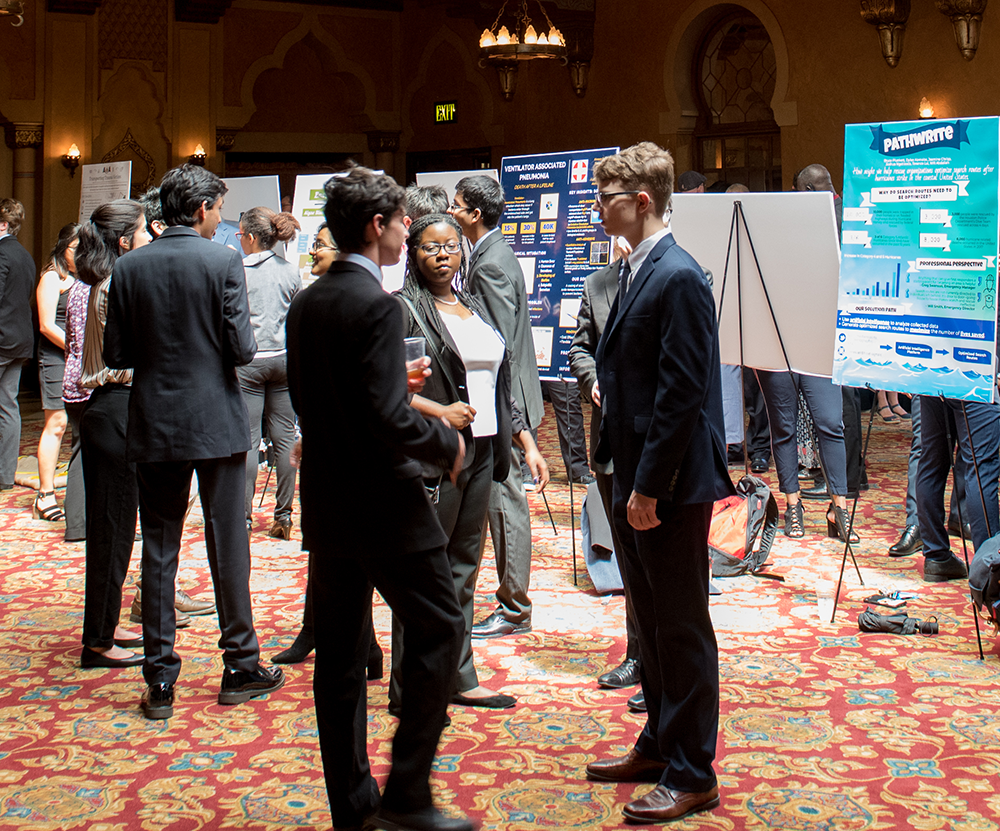 A group of students at a conference hall during a poster presentation.