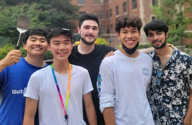 Five male students smiling. One is holding a spatula.